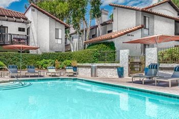 A swimming pool with chairs and umbrellas next to a resort style pool